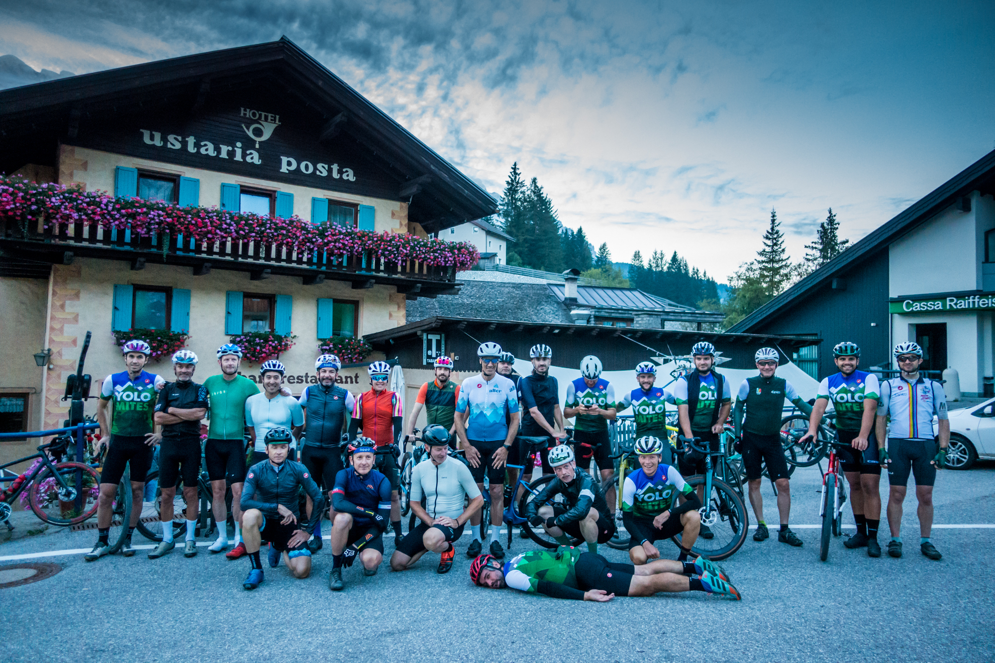 More than 20 cyclists pose for a photo in front of Hotel Ustaria Posta after riding the YOLOmites5000 bike ride. YOLOmites5000 is a backroads Dolomites cycling route that climbs 5,000 meters in just 80 miles (129 km). Founded by Igor Tavella of Hotel Ustaria Posta, this challenging ride is in September each year and set to the rising and setting of the sun. This is one of the most beautiful road and gravel cycling routes in Alta Badia and indeed in Italy's Dolomites.