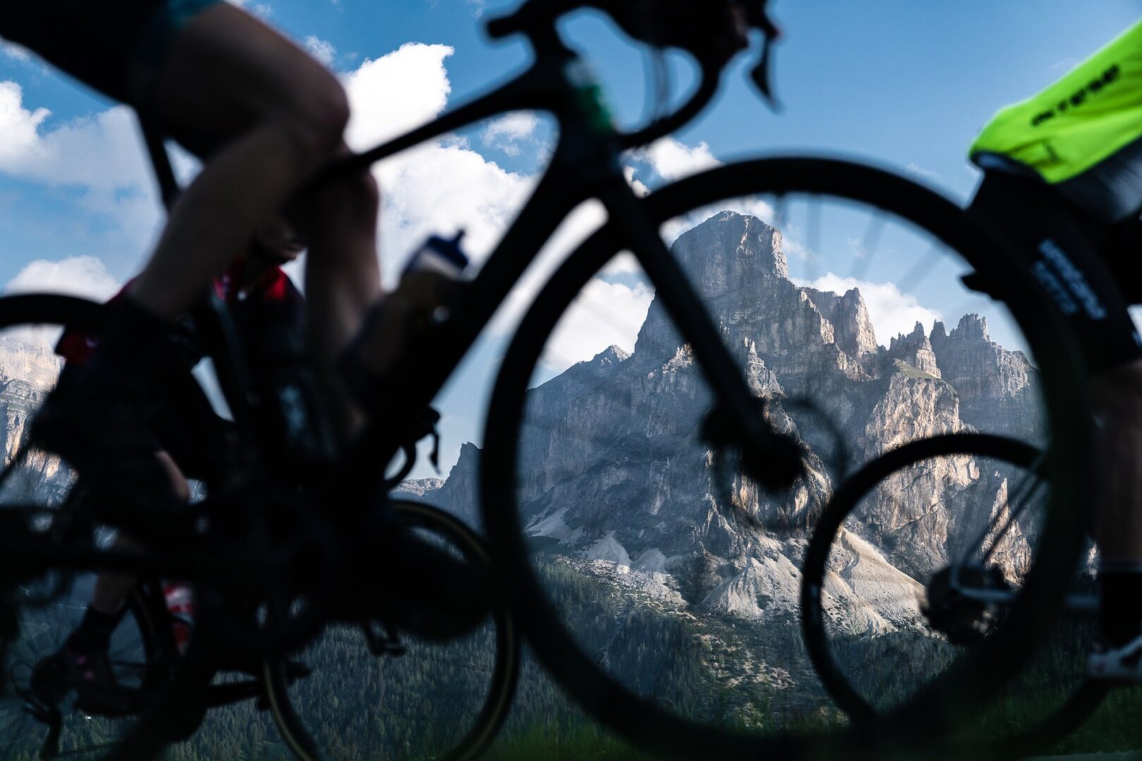 The peak of Sassongher is seen through the wheels of a cyclist during the Maratona dles Dolomiti, one of the most popular gran fondo cycling events in the world, featuring iconic climbs, stunning scenery, and exhilarating challenge. Starting in Corvara, Italy, the Maratona is an unforgettable experience for riders of all levels and rivals Italy's famous Giro d'Italia in popularity. But if you want to experience the best the Dolomites bike rides without the crowds and the high prices of mid-summer, explore Alta Badia with Alter Exploration.